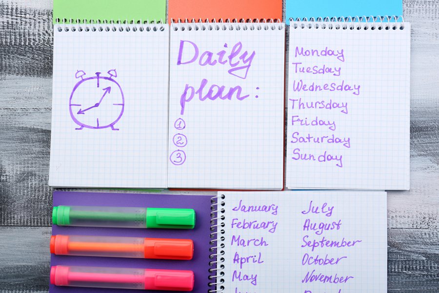 Notebooks with daily plan and markers on wooden table. Time management concept